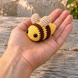 The bee lying on an open palm, an arm extending into the frame from the lower left.