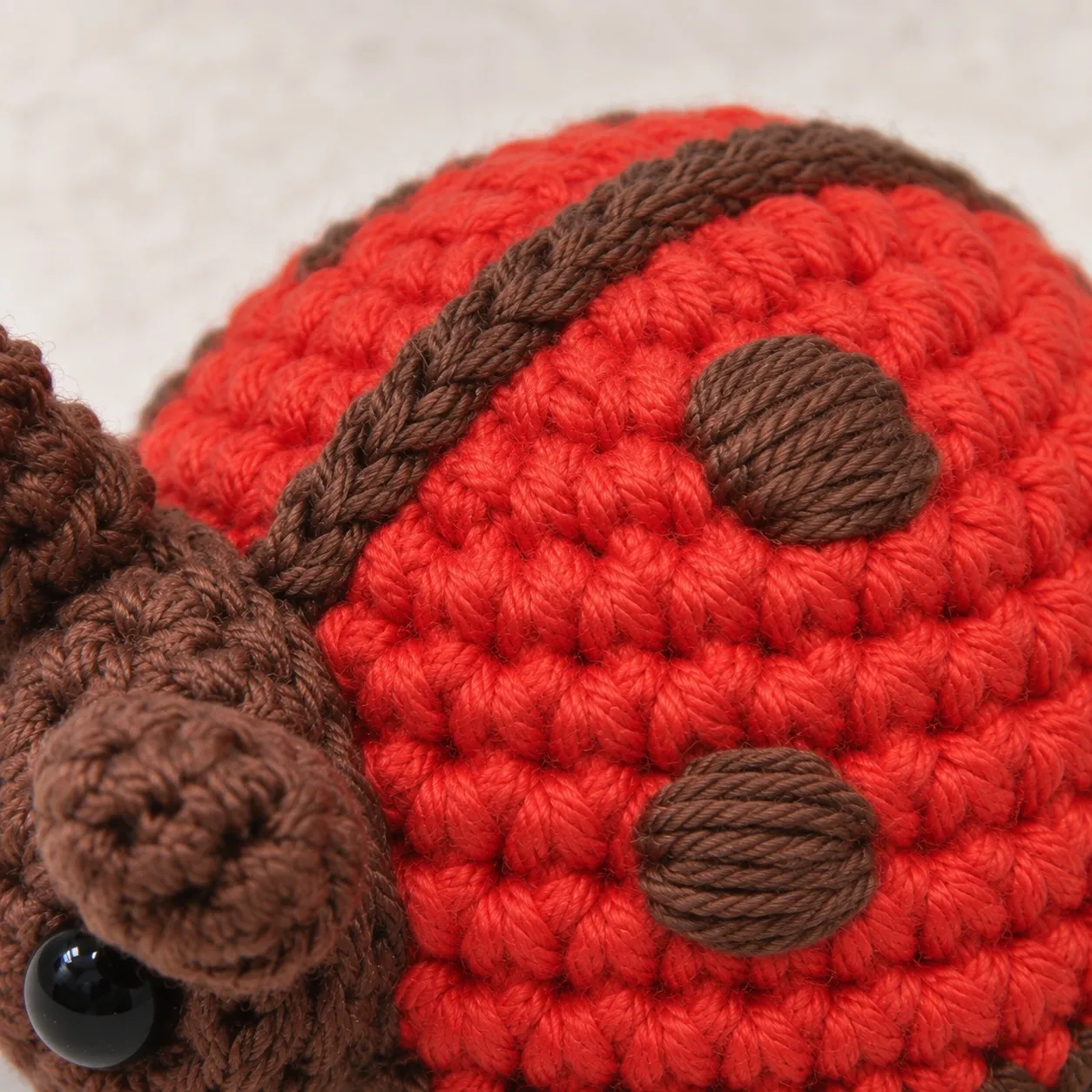 Close view of the red dome with two small round brown embroidered spots and a brown embroidered line running over the top.