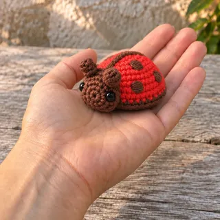 The ladybug standing on an open palm, an arm extending into the frame from the lower left.
